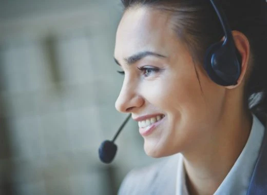 User support specialist wearing headset, smiling while helping customers in a call center setting